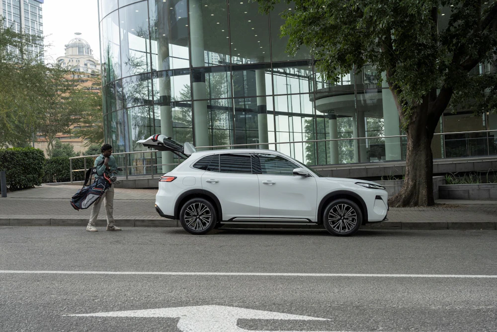 A white Geely SUV parked outside a modern city building